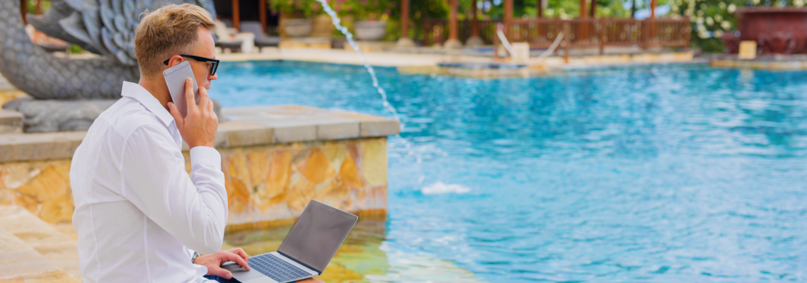 Abbildung ein Mann sitzt mit Laptop auf dem Schoß an einem Pool und telefoniert 